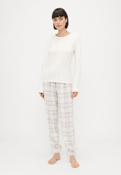 Off-white tričká s dlhým rukávom a trojivým zapínaním, spárované s ľahkými károvanými pyžamovými nohavicami s elastickými manžetami z jemného materiálu.