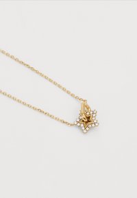 Collier en forme d'étoile dorée avec une chaîne, présentant un détail complexe et des pierres transparentes serties sur les bords de l'étoile.