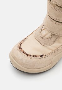 Beige nilkkurit, joissa on mokkaa ja kangasta, leopardikuosisella yksityiskohdalla, suljettu kärki ja säädettävät tarranauhat.