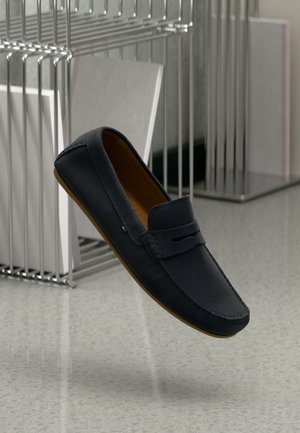 Marine læder loafers med brune gummisåler; rund tå, dekorativ syning og et frontudskæringsdetalje.