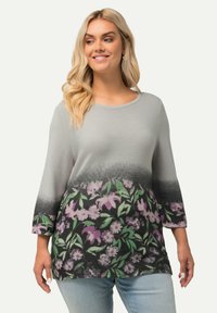 Lichtgrijze gebreide top met driekwartmouwen, met een bloemenpatroon in paarse en groene tinten aan de zoom, textuurstof.