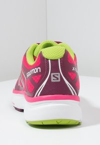 Bakvy av en Salomon X-Tour trail löparsko i mörkröd, rosa, limegrön och vit med tjock dämpande sula.