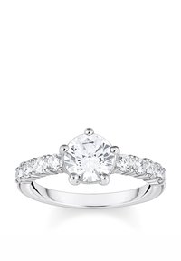 Anello di fidanzamento in oro bianco. Pietra centrale tonda con sei griffe, circondata da pietre più piccole lungo la fascia, finitura liscia e lucida.