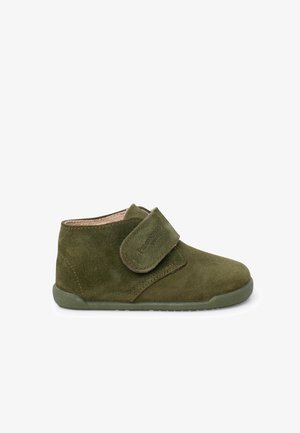 Green suede ankle boot with a Velcro strap, textured surface, rounded toe, and a flexible rubber sole for comfort and ease of movement.