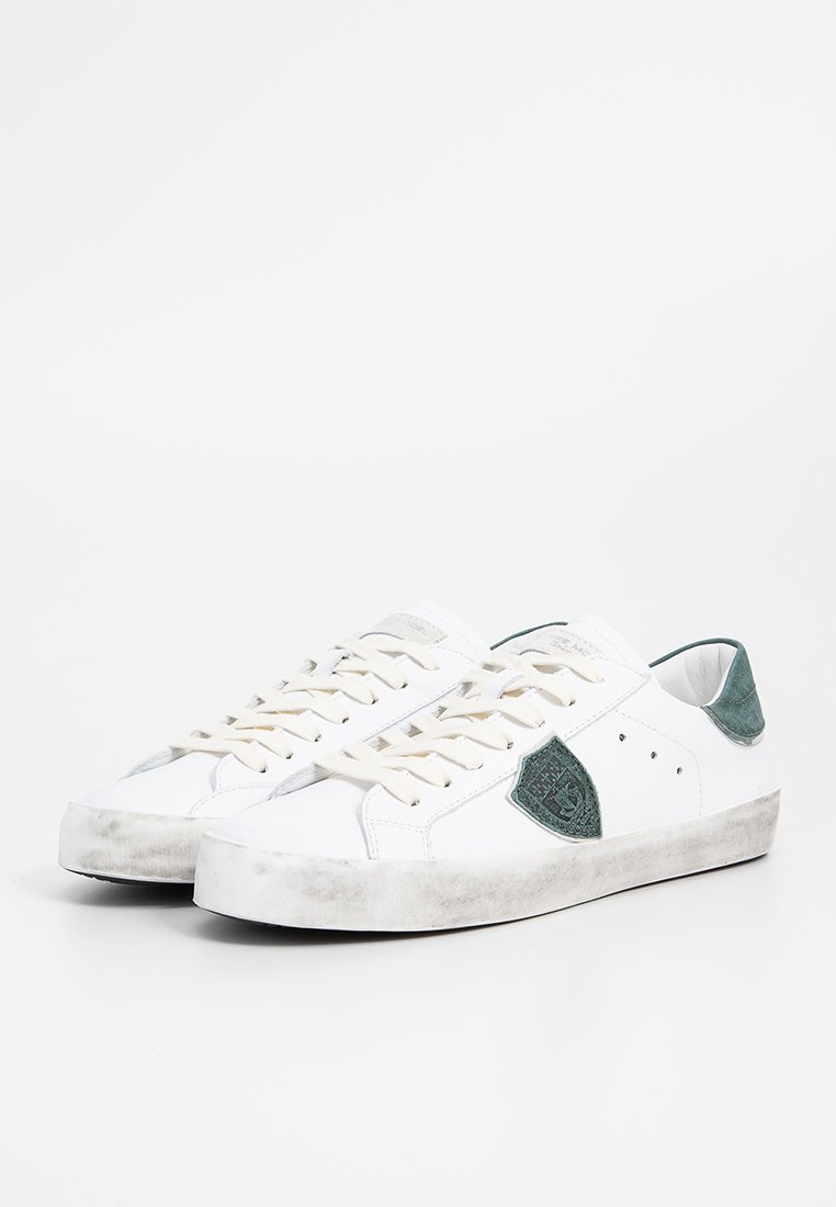 Sneakers bianchi in pelle con dettagli in suede verde sul tallone, caratterizzati da un pannello laterale testurizzato e lacci beige; leggermente usati, con suola abrasata.