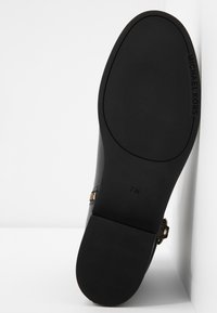 Semelle noire d'une chaussure Michael Kors avec une surface texturée antidérapante, taille 7M, et un petit talon carré, présentée sur un fond blanc.