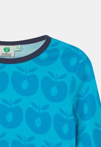 T-shirt de algodão turquesa com um padrão de maçãs em tom mais escuro, com um decote redondo canelado azul-marinho e etiqueta no interior.