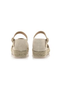 Espadrilles beige con suola in juta intrecciata, tomaia in tessuto e cinturino alla caviglia. Presentano un materiale in tela testurizzato e dettagli hardware minimi.