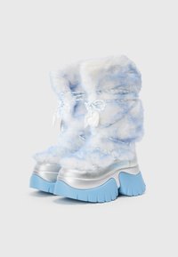 Silberne Plateauboots mit Kunstfell in Hellblau und Weiß, ausgestattet mit geflochtenen Schnürsenkeln und herzförmigen Anhängern an der Vorderseite.