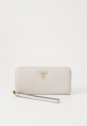 Portefeuille en simili cuir gris clair avec fermeture éclair, détail du logo triangulaire doré et attache pour poignet. Texture lisse et forme rectangulaire.