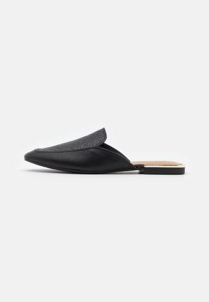 Mules en cuir noir avec une tige texturée présentant un motif en losanges, un bout pointu et un profil bas avec un accent métallique sur le talon.