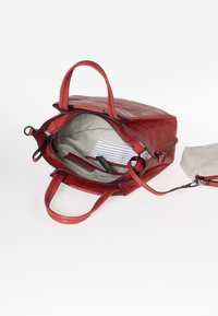 Borsa a tracolla rossa in pelle con doppi manici, chiusura con zip, fodera in tessuto a righe e una piccola pochette rimovibile. L'interno comprende tasche.