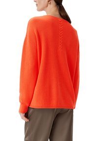 Jasnopomarańczowy, oversize sweter o teksturowanym splocie, z plecionym wykończeniem przy dekolcie z tyłu oraz ściągaczami przy mankietach i u dołu.