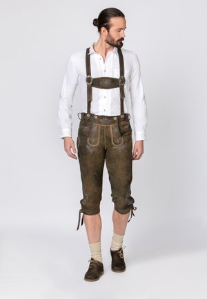 Brown leather lederhosen with decorative stitching, adjustable straps, and buttons. Worn with a white shirt and brown shoes.