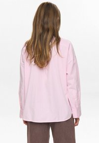 Roze en witte gestreepte oversized blouse met lange mouwen, knopen bij de manchetten en een gebogen zoom, vervaardigd uit een gladde stof met een zachte textuur.