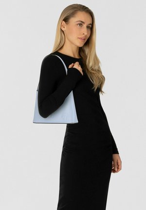 Lichtblauwe leren handtas met een driehoekige vorm, zwarte afwerking en een subtiel geperst ontwerp, gedragen door een model in een zwarte jurk.