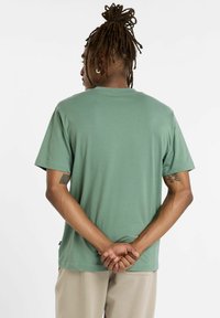 Kortærmet t-shirt med rund hals i en afdæmpet grøn farve, lavet af blødt materiale med en afslappet pasform. Har et minimalistisk design uden synlige mønstre.