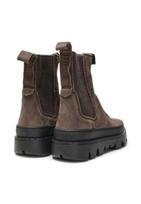 Botas de tobillo de ante marrón con paneles elásticos en los laterales, suela gruesa de goma negra y una marca en relieve en la parte trasera.