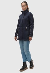 Mornarsko modra flisasta jakna z visokim ovratnikom, žepom na zadrgo in obliko slim fit. V kombinaciji z svetloblue jeansom in črnimi čipkastimi škornji.