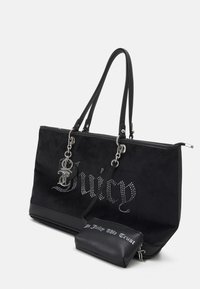 Black tote bag with studded "Juicy" logo, double handles, attached small pouch reading "In Juicy We Trust," silver keychain details.