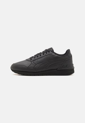 Basket basse noire Puma avec laçage sur le devant, logo latéral texturé et semelle rembourrée sur un fond clair uni.