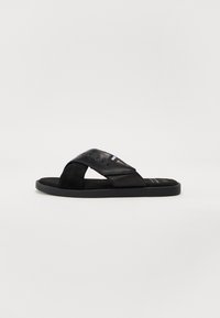 Svarte sandaler laget av lær og semsket skinn, med et kryss-design på stroppene og en flat gummisåle med preget logo og trikolor akcent.