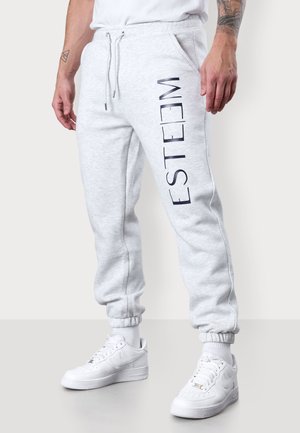 Graue Sweatpants mit einer weichen Textur, ausgestattet mit einem vertikalen navy Druck, der "ESTEEM" am linken Bein zeigt. Elastische Bündchen und verstellbarer Kordelzug am Bund.