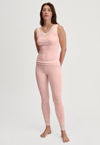 Roze geribbelde tanktop met een kanten decolleté, gecombineerd met bijpassende leggings met kantaccenten aan de zoom. Zachte stof en een aansluitend ontwerp.