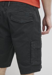 Svart cargo-shorts laget av bomull-blandingsstoff, med flere lommer, kontraststing og en avslappet passform.