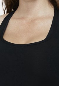 Top senza maniche nero con un ampio scollo rotondo e una texture morbida e liscia. Il tessuto sembra elasticizzato e aderente.