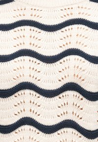 Tissu en maille crème avec des rayures horizontales ondulées bleu foncé et des motifs en dentelle délicats en forme d'éventail.