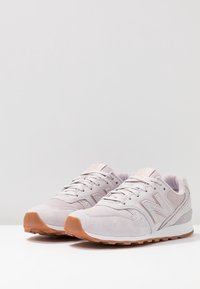 Helles rosa Wildleder-Sneaker mit Gummisohle, ausgestattet mit einem strukturierten Obermaterial, Schnürverschluss und einem auffälligen 'N'-Logo an der Seite.
