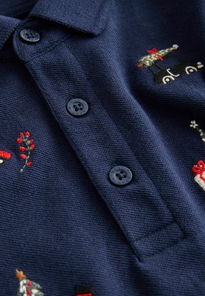 Mörkblå polotröja med tre svarta knappar, prydd med färgglad broderi av träd, gåvor och blommönster över tyget.