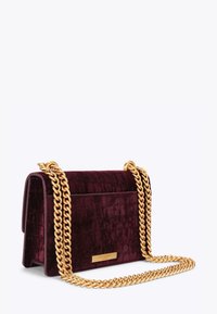 Bordo aksamitna torebka o fakturze krokodyla, z złotym łańcuszkiem na ramię oraz złotą plakietką z nazwą marki.