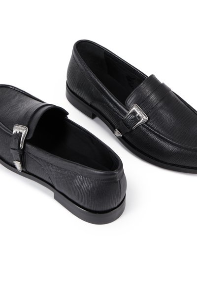 Sorte loafers har en tekstureret læderoverdel, sølvfarvet spænde og en lavprofil sål. Designet fremhæver en glat finish og en struktureret form.