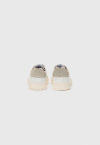 Sneakers med en strukturert grå overdel, hvite lærpaneler og en kremfarget gummisåle. Har subtil merking på hælen og et minimalistisk design.