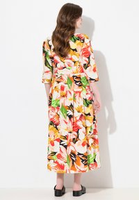 Maxikleid mit Blumenmuster in lebhaften Farben wie Orange, Gelb, Grün und Schwarz. Breite Ärmel und eine taillierte Taille betonen den fließenden Stoff.