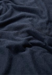 Tmavě modrá texturovaná látka s měkkými, splývavými vlastnostmi a viditelnými záhyby, což naznačuje lehký textil vhodný pro oděvy nebo čalounění.