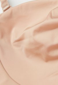 Lichtroze stof met een gladde textuur, licht gekreukt. Beschikt over dunne bandjes en laat een zachte, rekbare ontwerp zien.