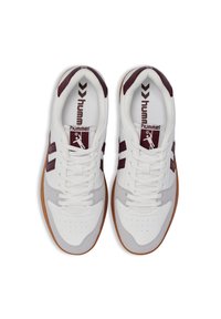Witte en bordeauxrode sportschoenen met een gestructureerde grijze acccent, voorzien van een geperforeerde teen, veters en een gumrubberen zool. Hummel-logo op de tong.
