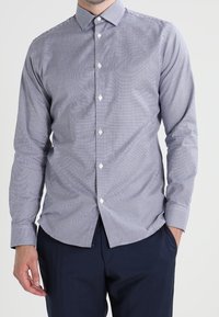 Niebieska i biała w kratkę koszula z długim rękawem z zapięciem na guziki, z klasycznym kołnierzykiem i białymi guzikami. Wykonana z bawełnianej tkaniny.