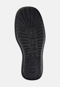 Suola di scarpa in gomma nera con un motivo radiale, logo "CAMPER" in rilievo e taglia "38" sul tallone.
