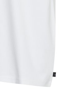 Camiseta de algodón blanca con una textura suave, mangas cortas y un corte recto. Incluye una pequeña etiqueta negra en la costura lateral.