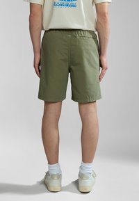 Khaki shorts made of lightweight fabric, featuring an elastic waistband and side pockets, with a simple, unadorned design.