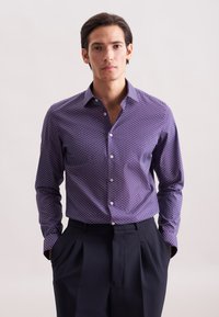 Maglietta a maniche lunghe viola con un motivo geometrico in rosso e bianco, realizzata in un tessuto liscio, con colletto alla francese e chiusura con bottoni.