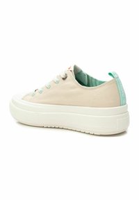 Zapatillas de lona en color crema con cordones verde menta, suela blanca gruesa y paneles laterales texturizados. Presenta un bucle en el talón verde y un interior a rayas.