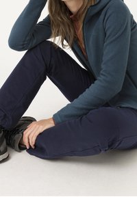 Blue fleece jacket with a hood, red shirt underneath, and navy pants. Black hiking boots with grey accents are visible.
