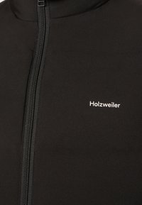 Schwarze Daunenjacke mit hohem Kragen, durchgehendem Reißverschluss und weißem "Holzweiler"-Logo auf der Brust. Glatte, matte Textur.