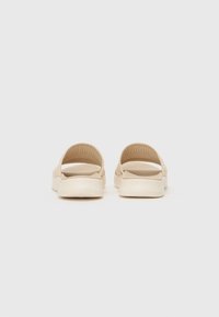 Brune slip-on sandaler med en teksturert stoffoverdel, åpen hæl og fleksibel gummisåle. Minimalistisk design med en pustende struktur.