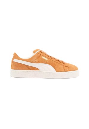 Lichtbruine suède Puma sneaker met witte streep, veters en rubberen zool, gezien vanaf de zijkant op een witte achtergrond.